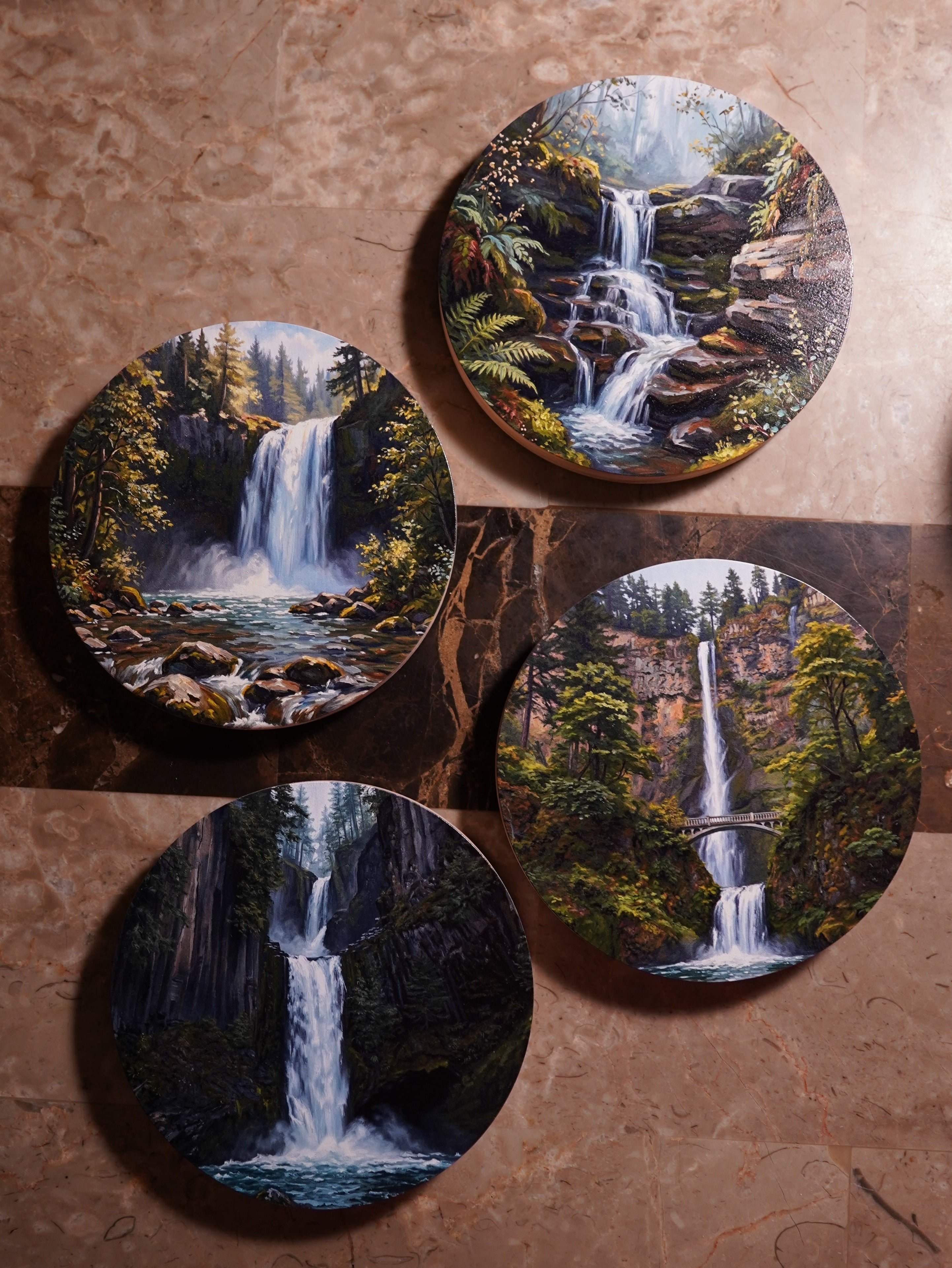 Four round coasters with nature-themed designs on a wooden surface.
